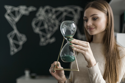 Junge Frau hält Sanduhr in den Händen.