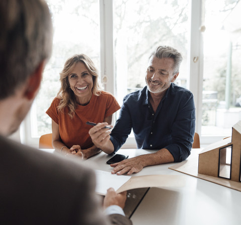 Wir unterstützen Sie bis zum Notartermin und darüber hinaus. Paar unterschreibt Vertrag beim Notar